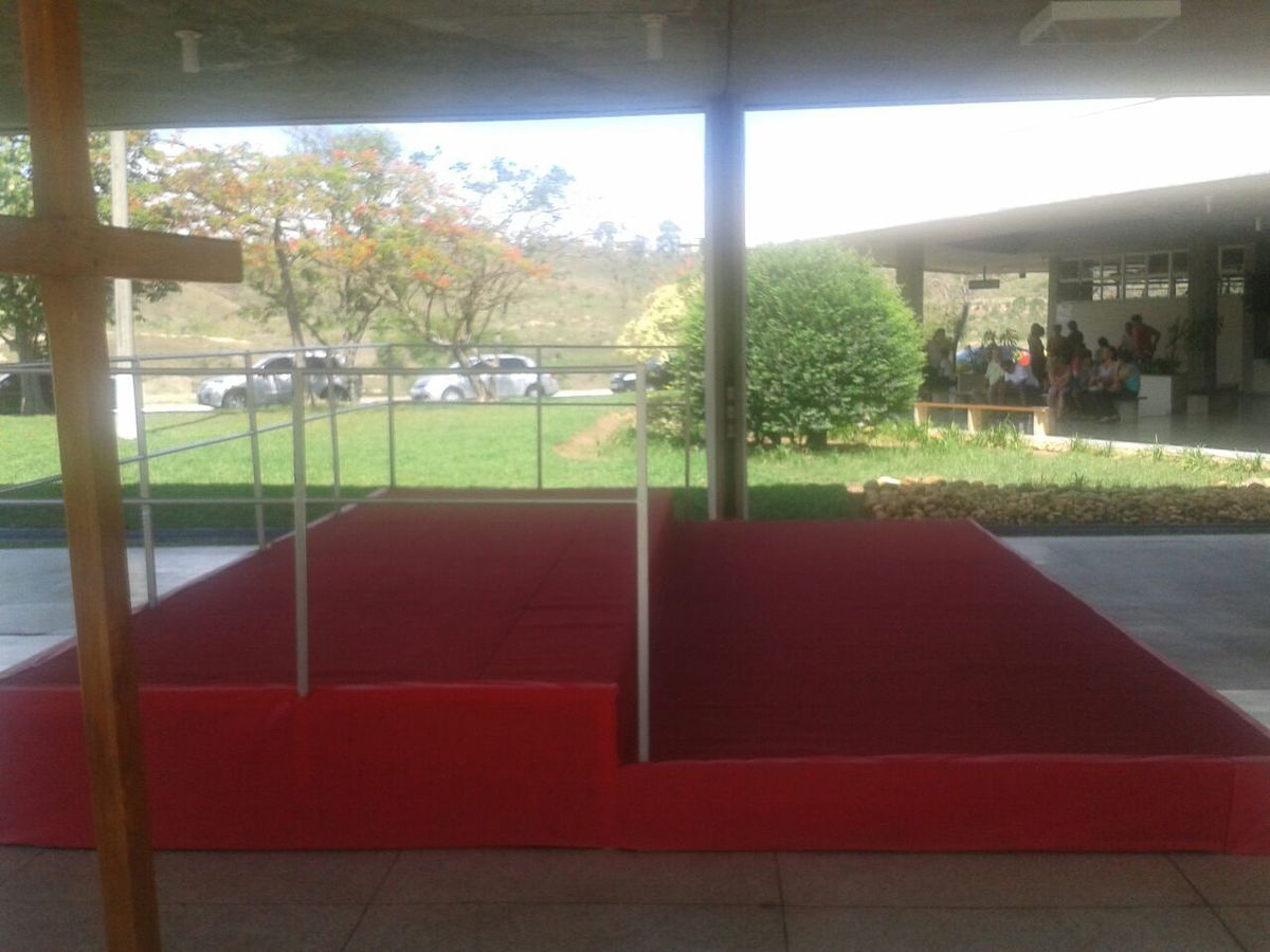 Palco montado em área externa com piso vermelho
